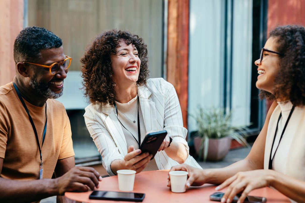 Group of attendees laughing and looking at phone
