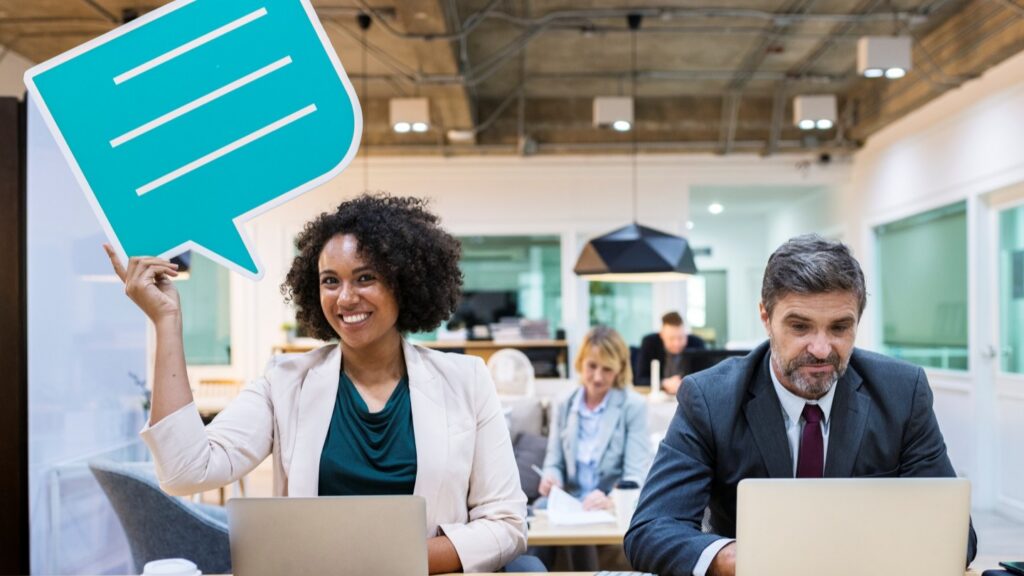 Two employees, one looking at a laptop the other at the camera and smiling